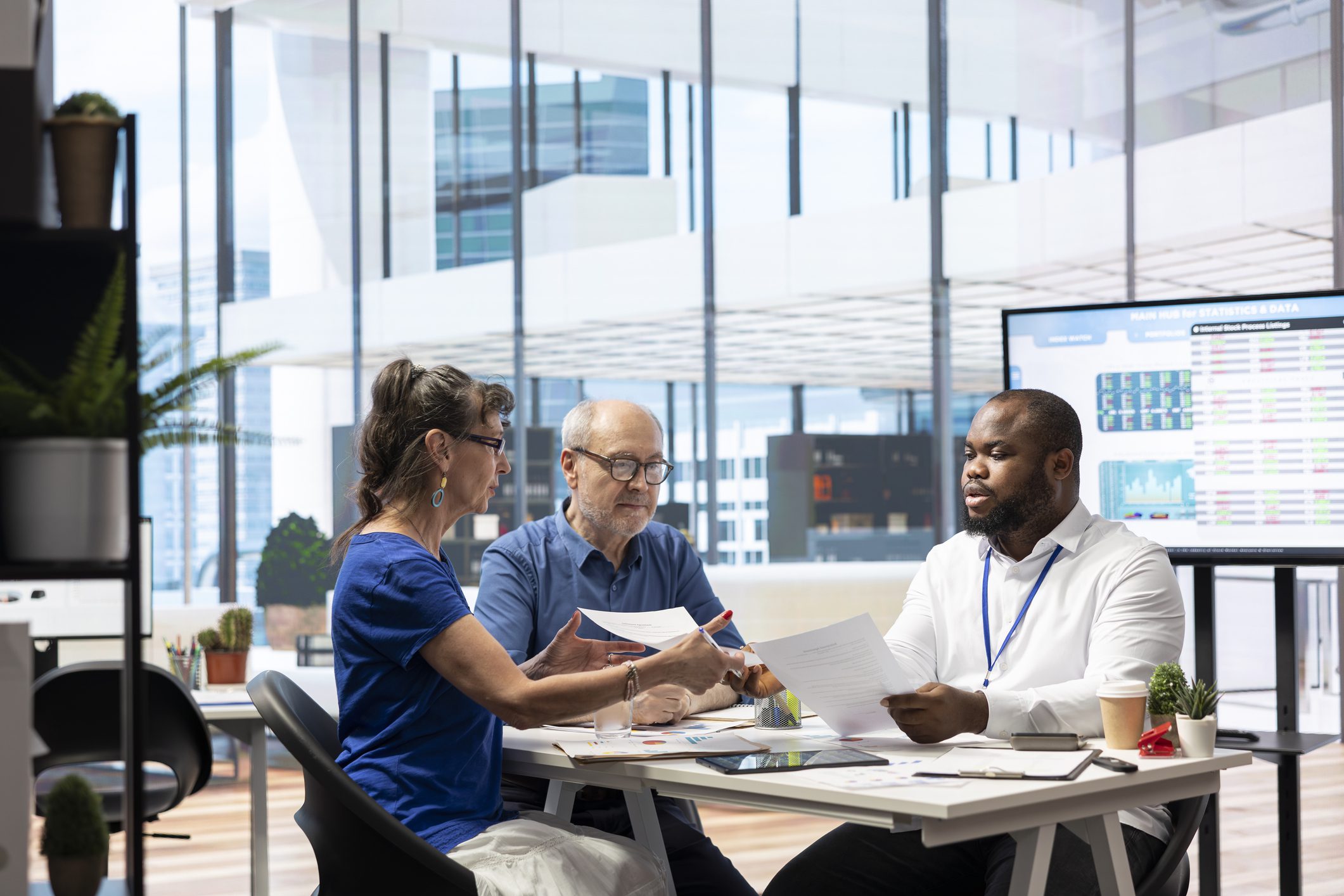 Three medical professionals discussing patient charts in a bright office.