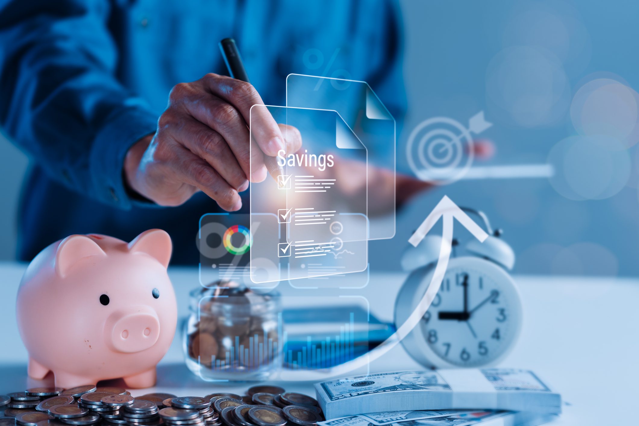 Person holding glass of water with coins and piggy bank on table symbolizing financial growth.