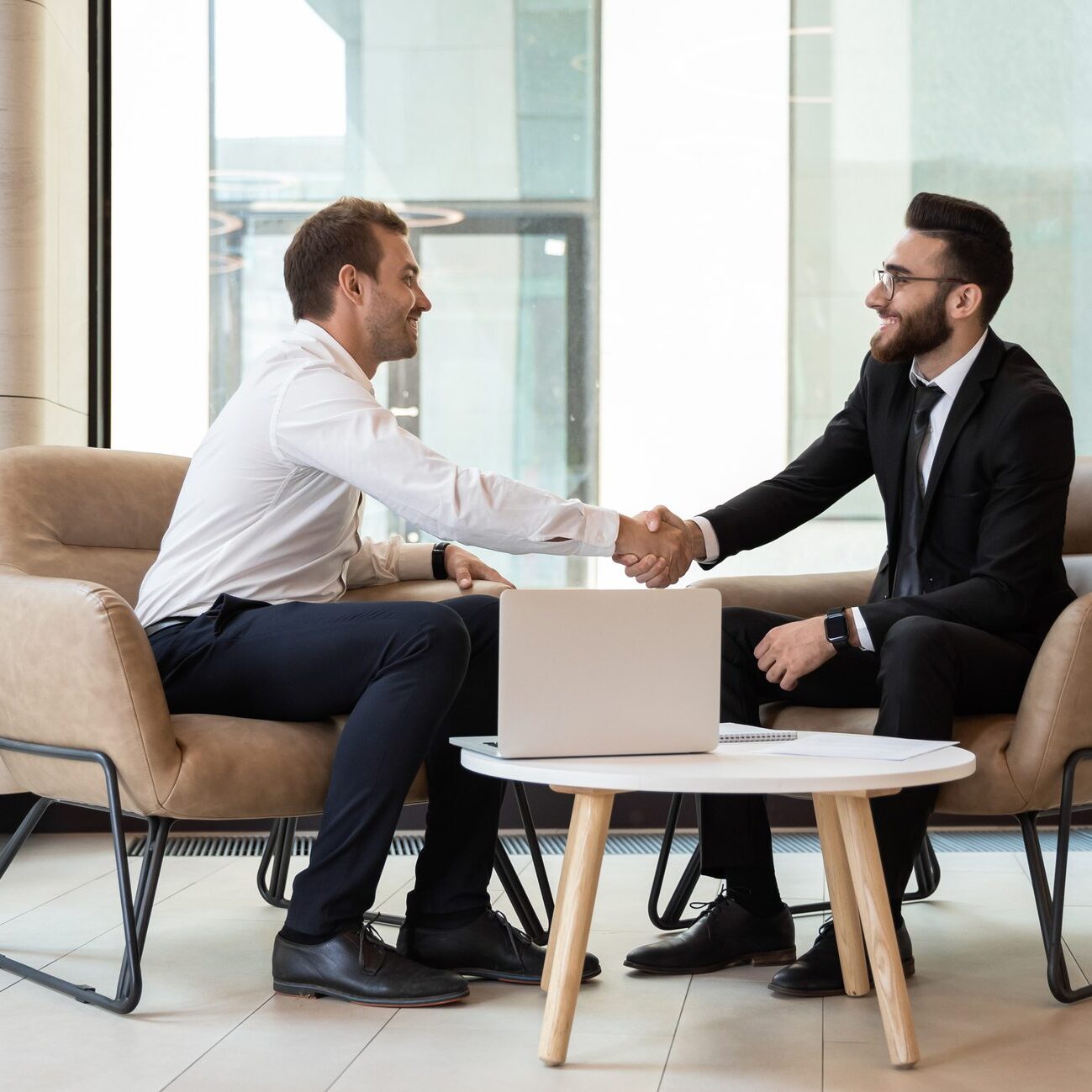 Two businessmen shaking hands in a modern office setting.
